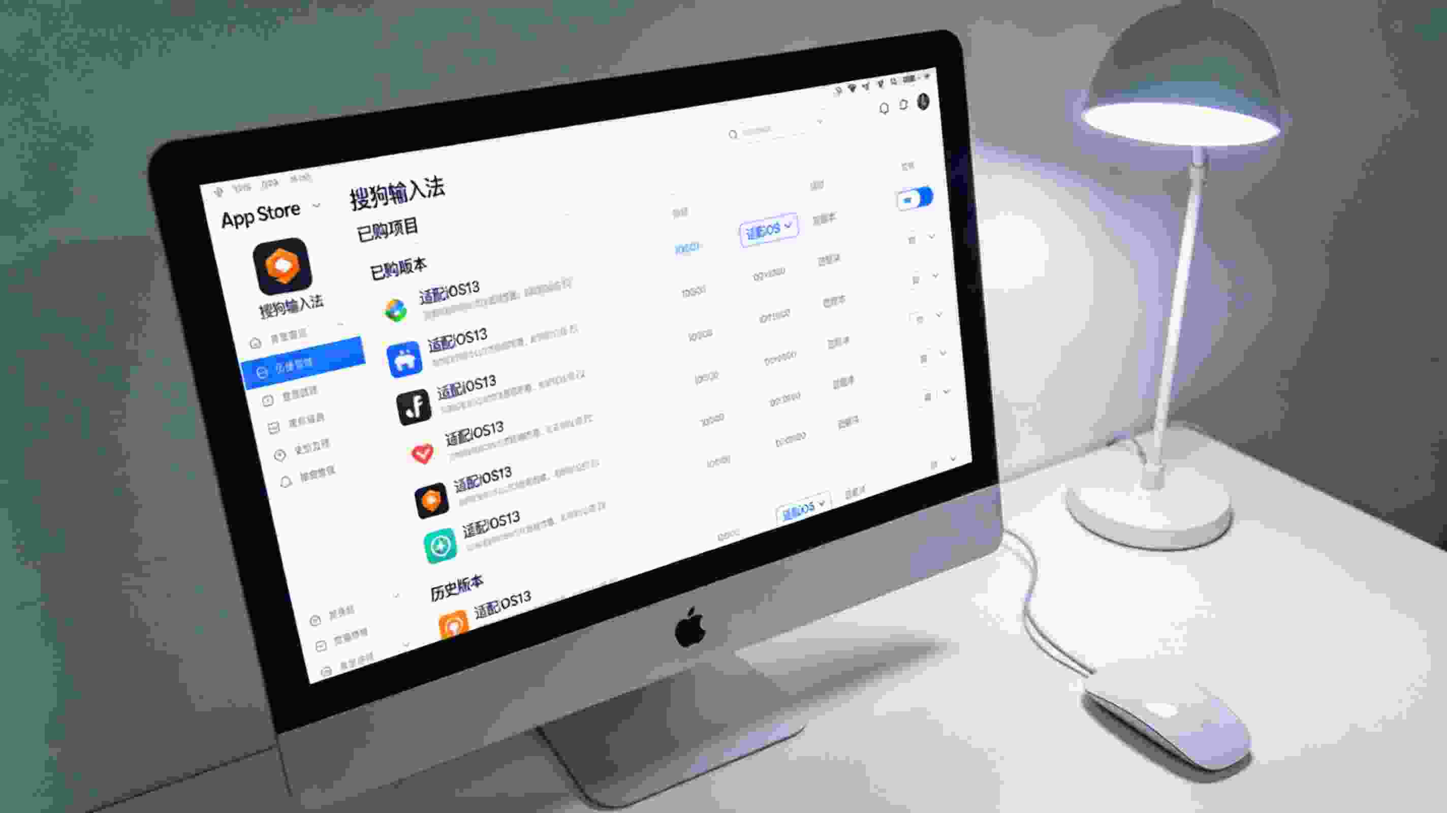 电脑屏幕显示App Store里的搜狗拼音输入法页面，页面展开已购项目的历史版本列表，其中显示适配iOS13的版本选项，旁边放着有线鼠标，台灯冷光