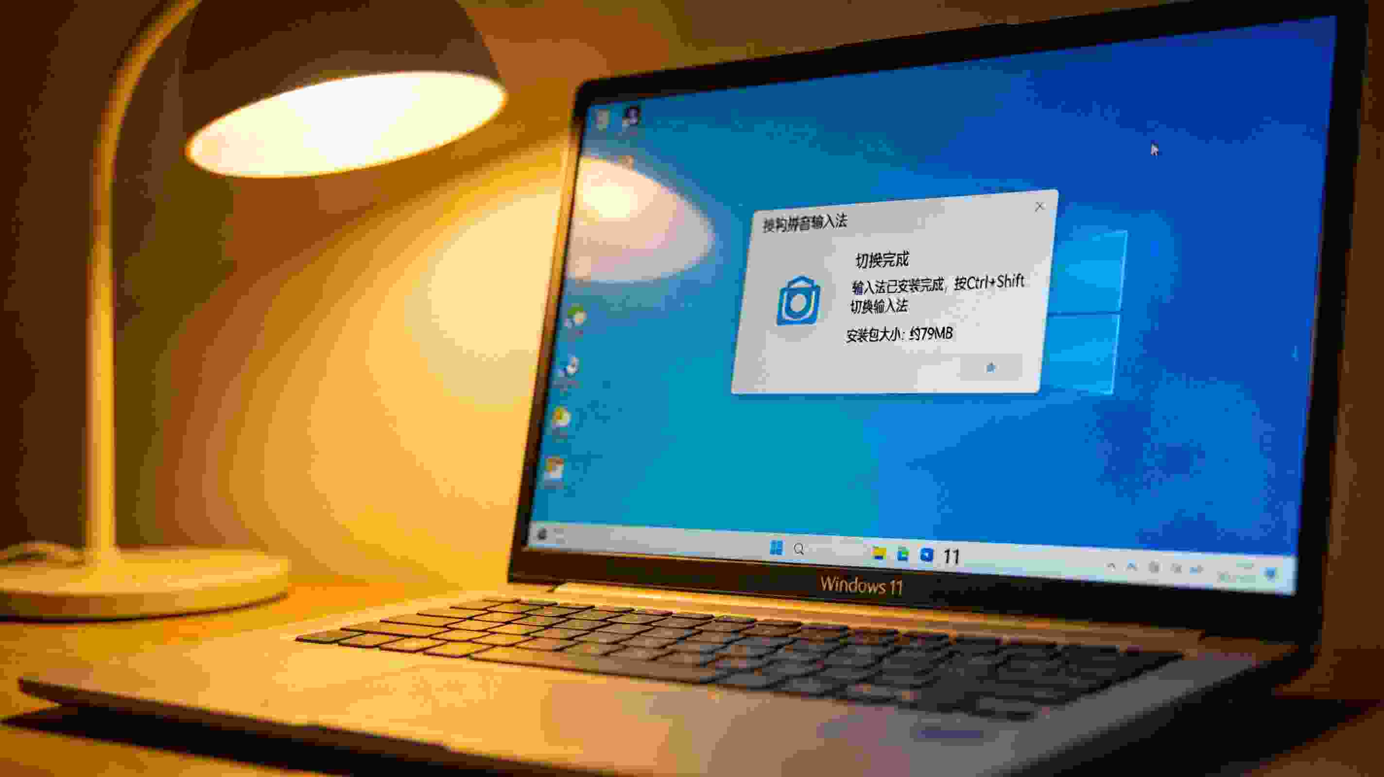 桌面的Windows11系统电脑，屏幕显示搜狗拼音安装完成后的输入法切换提示框，旁边显示安装包大小为不到80MB，台灯暖光