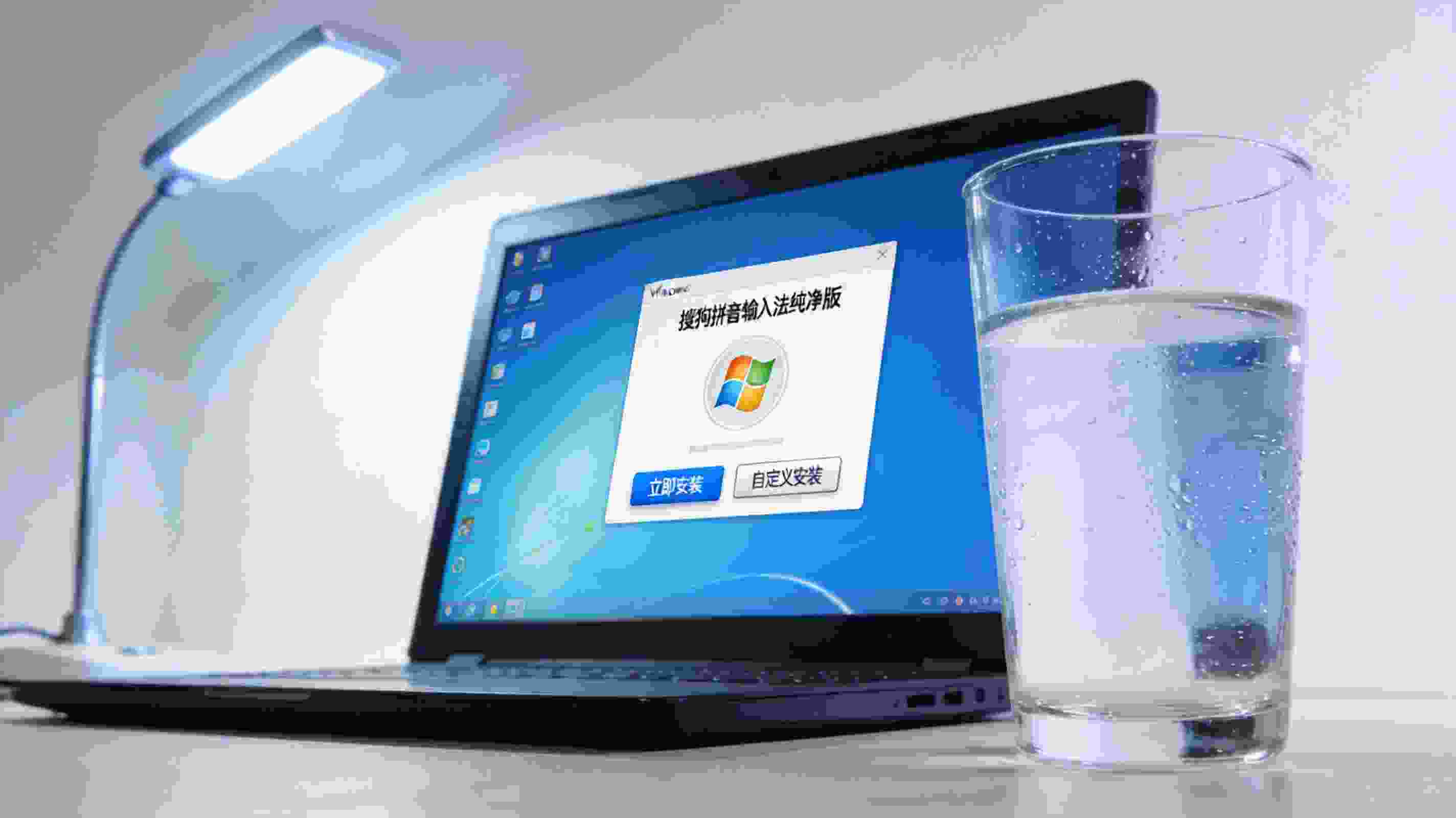 电脑屏幕显示Windows系统下的搜狗拼音输入法纯净版安装界面，桌面放着半杯温水，台灯冷光