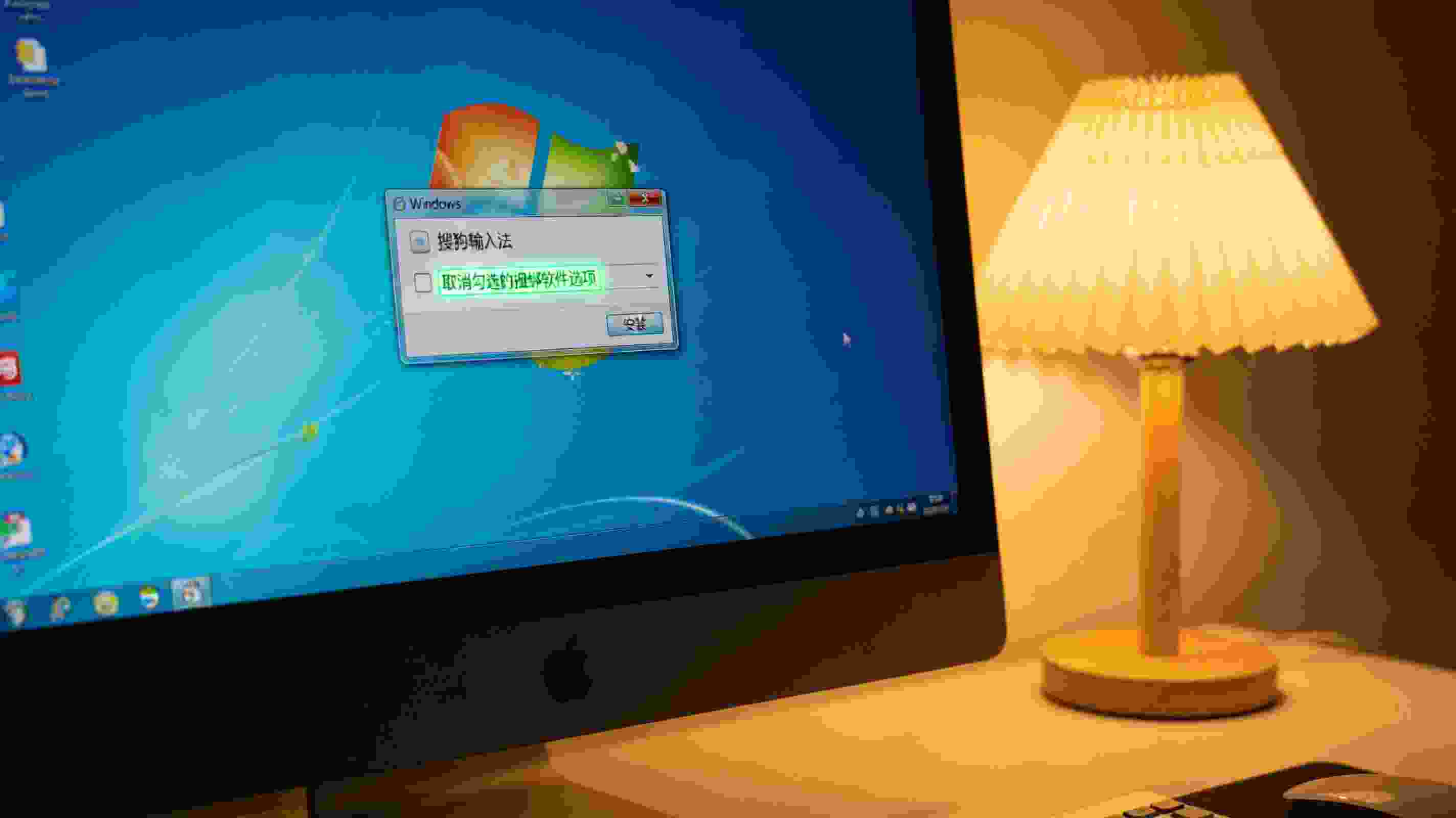 桌面的Windows系统电脑，屏幕显示搜狗拼音输入法安装界面，取消勾选的捆绑软件选项亮着，旁边有台灯暖光