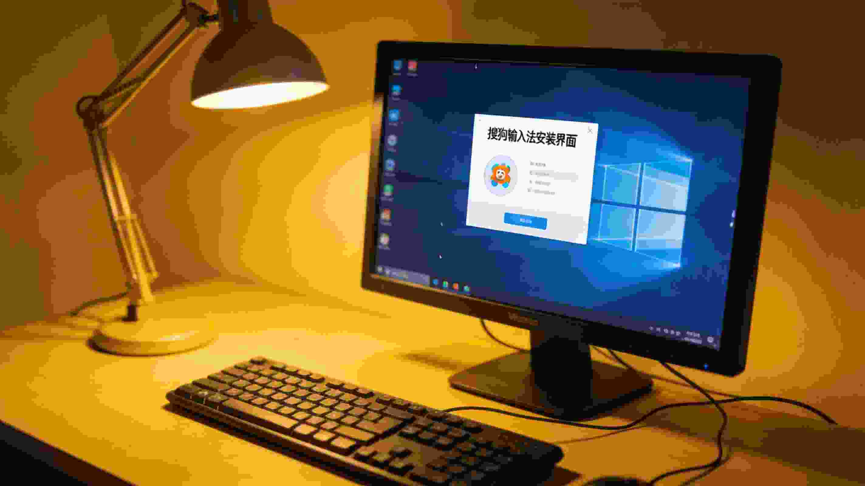 桌面的Windows系统电脑，屏幕显示搜狗拼音输入法安装界面，旁边摆着有线键盘，台灯暖光