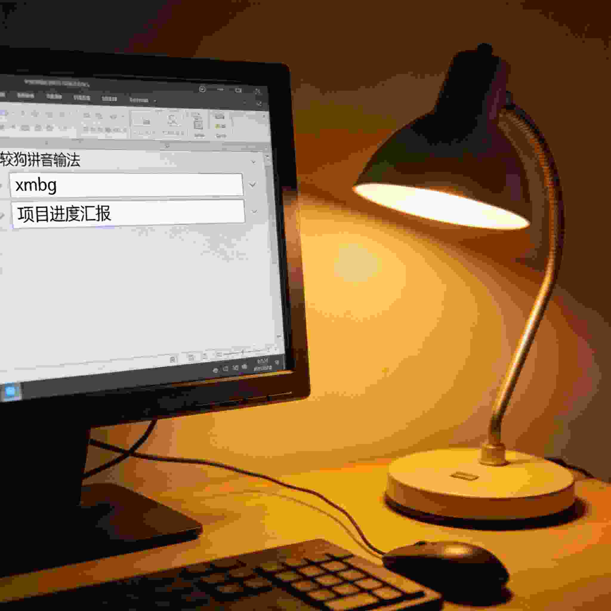 电脑屏幕显示搜狗拼音输入法自定义短语设置界面，输入框里有“xmbg”和“项目进度汇报”，旁边摆着普通台灯，暖光